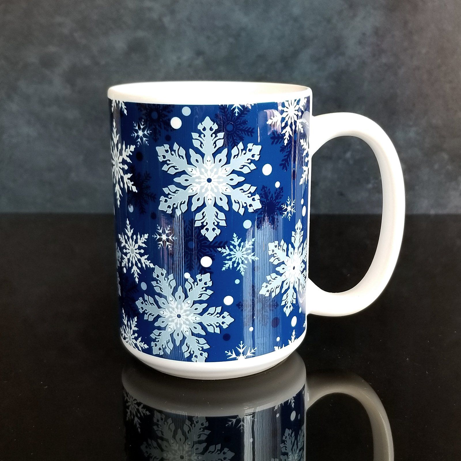 Classic Blue Snowflake Pattern Winter Mug (15oz) on glassy black and midnight background. A ceramic coffee mug designed with a pattern of different shades of blue snowflakes over a classic blue background color that wraps around the mug.