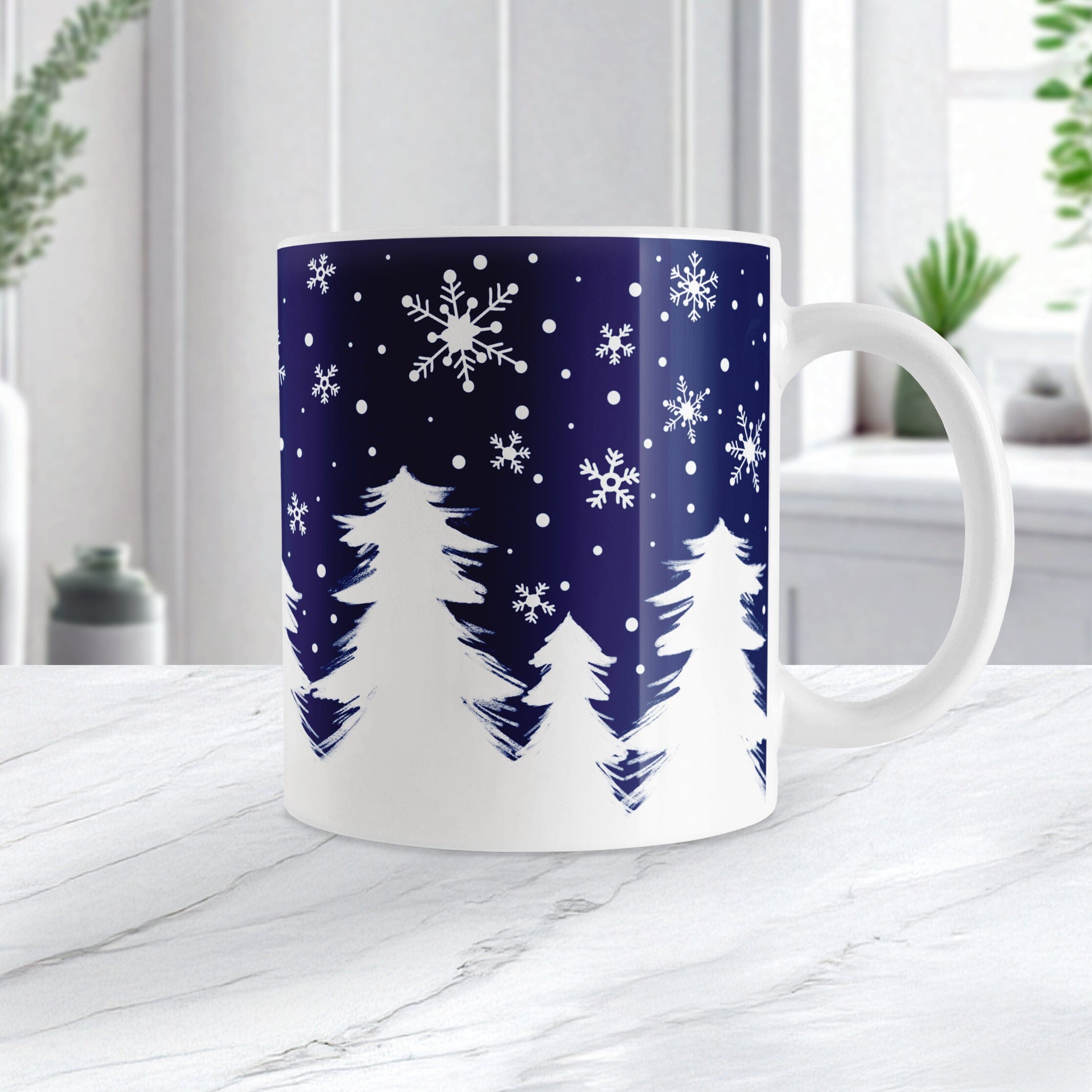 White mug with winter design featuring trees and snowflakes on a blue background, placed on a white surface.